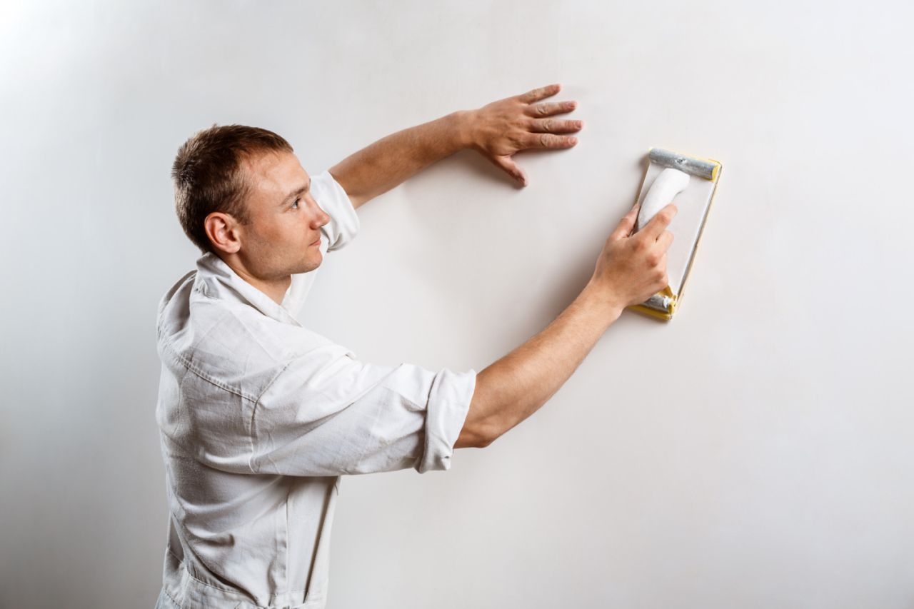 worker grinding white wall with sandpaper (1)